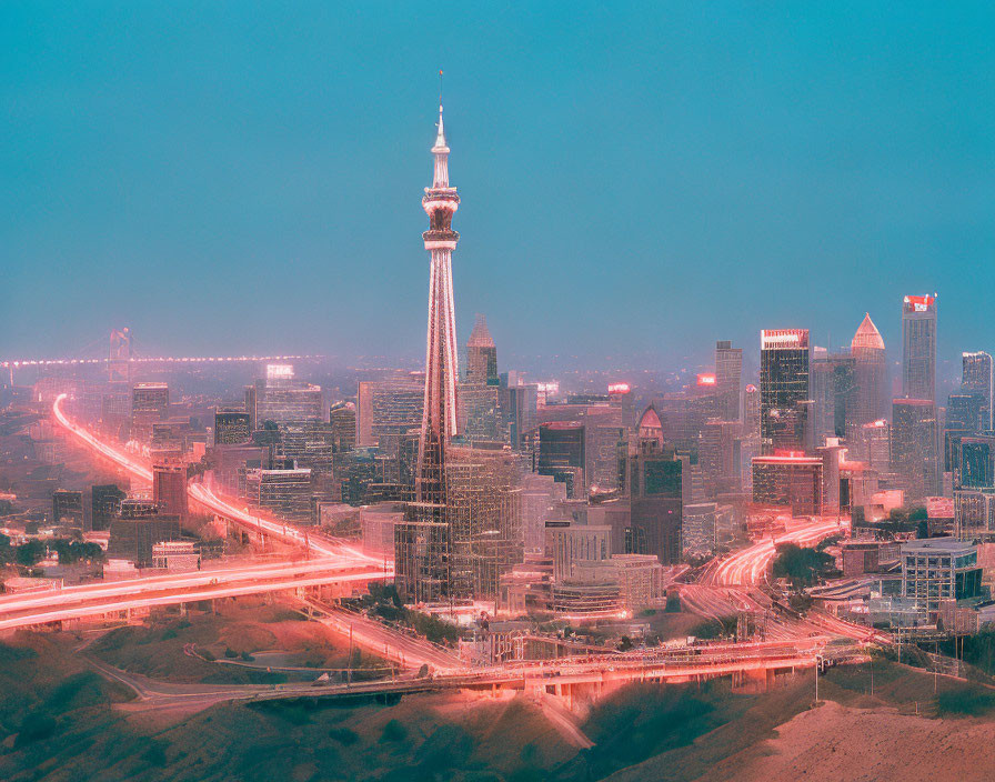 City skyline at dusk with illuminated tower and traffic lights.