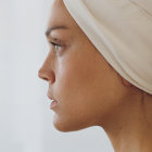 Woman with head wrap covered in water droplets near pool