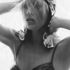 Monochrome image of girl in floral swimsuit with swim cap, water droplets, hands behind head