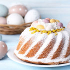 Pastel-colored Easter eggs in wicker basket with spring flowers.