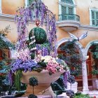 Ornate Fountain Surrounded by Lush Flowers and Classical Building