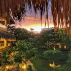 Illuminated wooden cabins in lush tropical forest at sunset