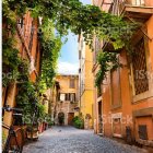 Vibrant yellow houses on cobblestone street with greenery and blue sky