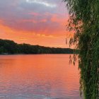 Tranquil sunset reflected in water by illuminated cliff at night