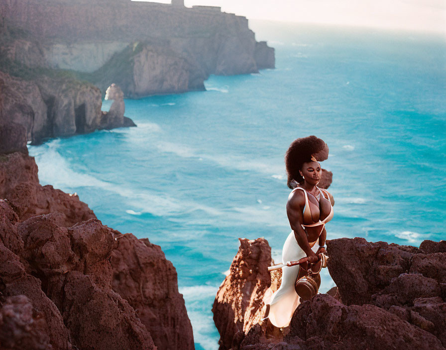 Woman in White Poses on Rocky Cliffs by Serene Blue Sea