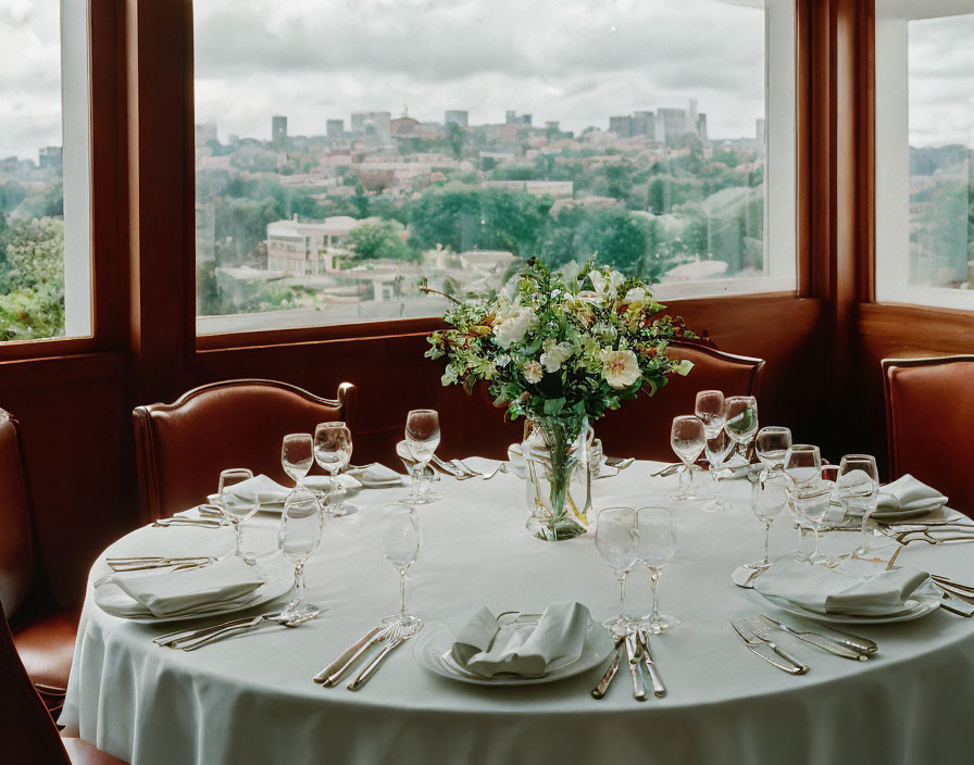 Sophisticated dining table with floral centerpiece and city view.