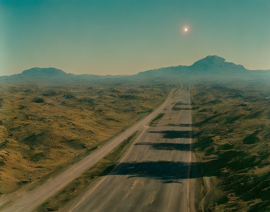 Desolate highway in rugged desert landscape under hazy sky