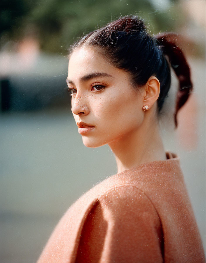 Portrait of woman with thoughtful expression and tied-back hair in soft, warm lighting