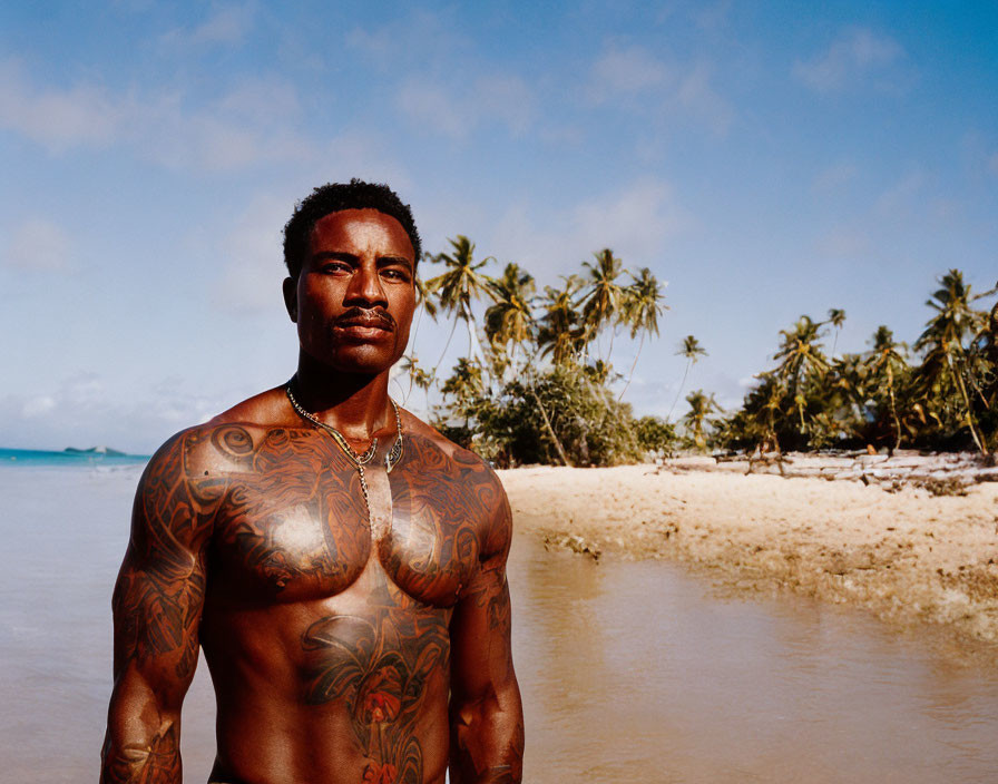 Tattooed shirtless man on beach with palm trees and blue sky