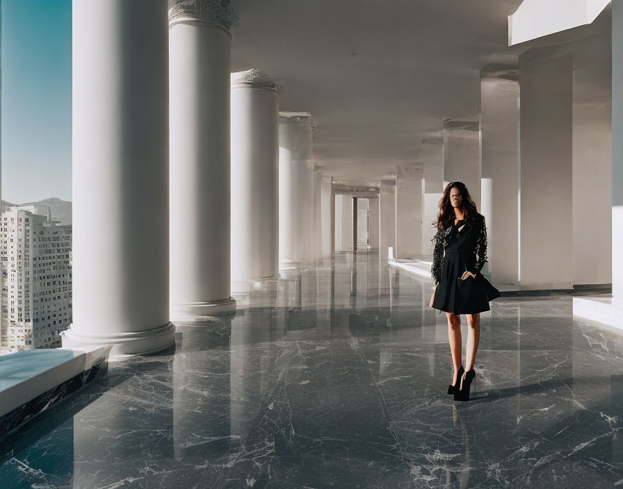 Woman in Black Dress in Sunlit Hall with White Columns and Buildings Outside