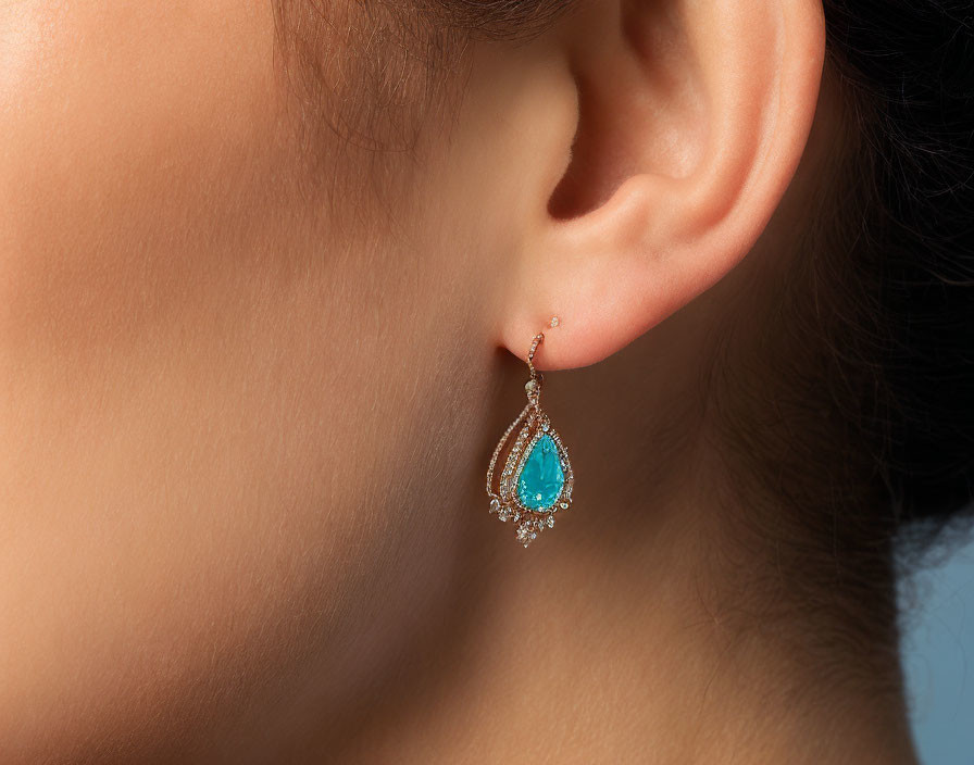 Woman's ear with turquoise stone earring surrounded by diamonds