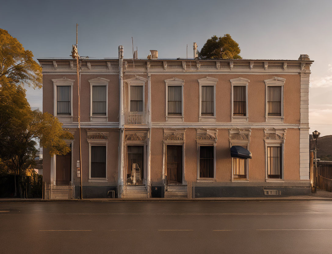 Classical two-story building with symmetrical windows at hazy sunset