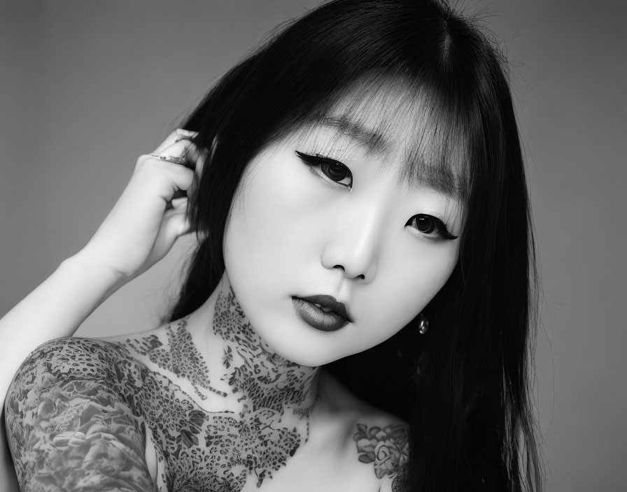 Monochrome portrait of Asian woman with floral chest tattoo and bold makeup