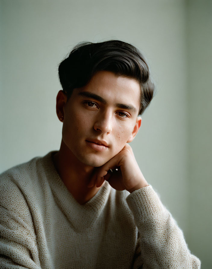 Styled Hair Young Man in Beige Sweater on Soft Green Background