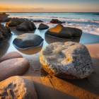 Scenic sunset on rocky beach with waves under golden sky