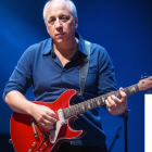 Man Playing Red Electric Guitar on Stage in Dark Blue Shirt