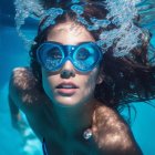 Person with blue goggles underwater surrounded by bubbles