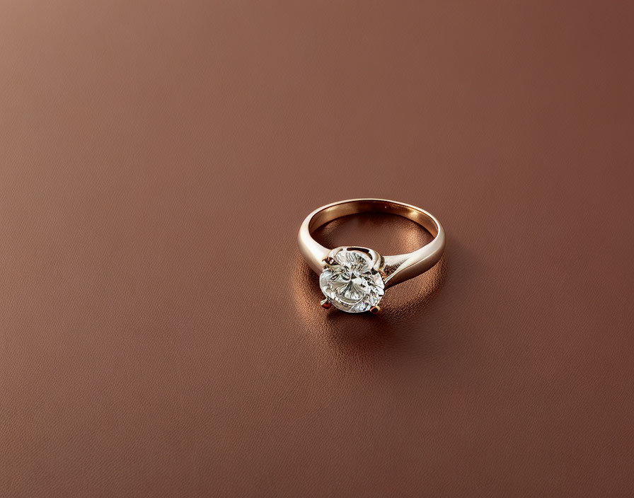 Solitary Gold Ring with Diamond Centerpiece on Brown Background