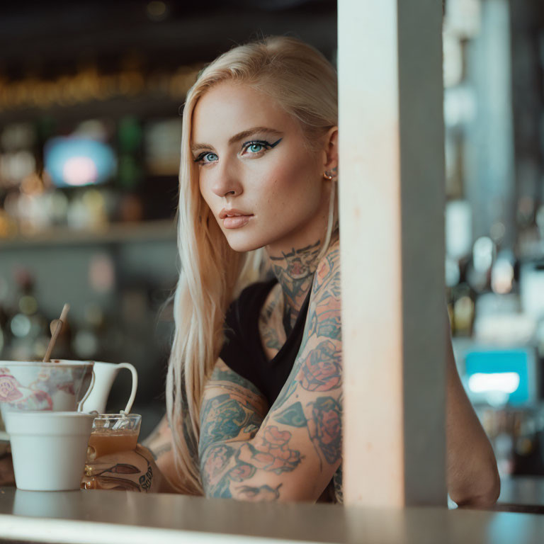 Blonde Woman with Sleeve Tattoos Drinking Tea at Bar