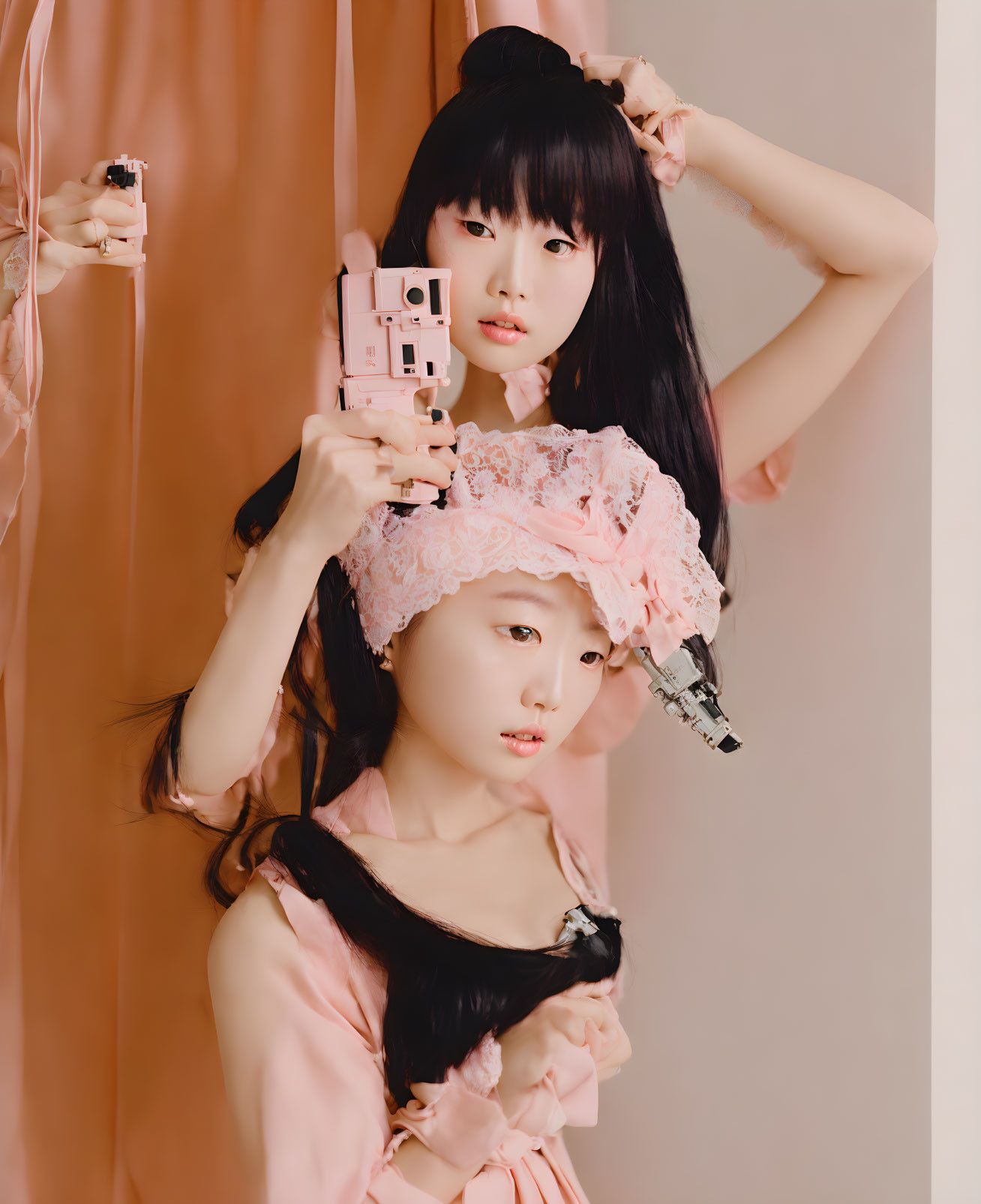 Two individuals posing in pink-themed setting, one taking selfie with pink camera, other peeping from behind