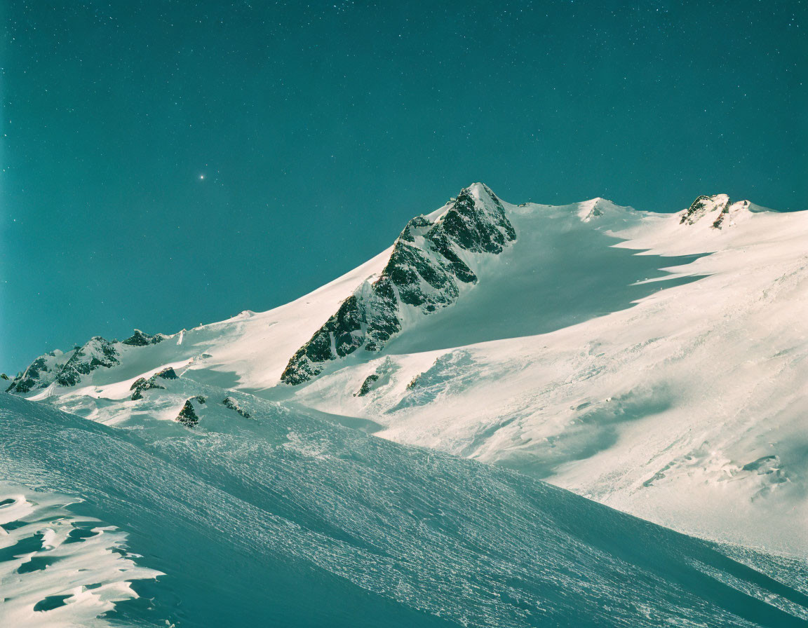 Snow-covered mountain landscape under clear blue sky with falling snow or stars.