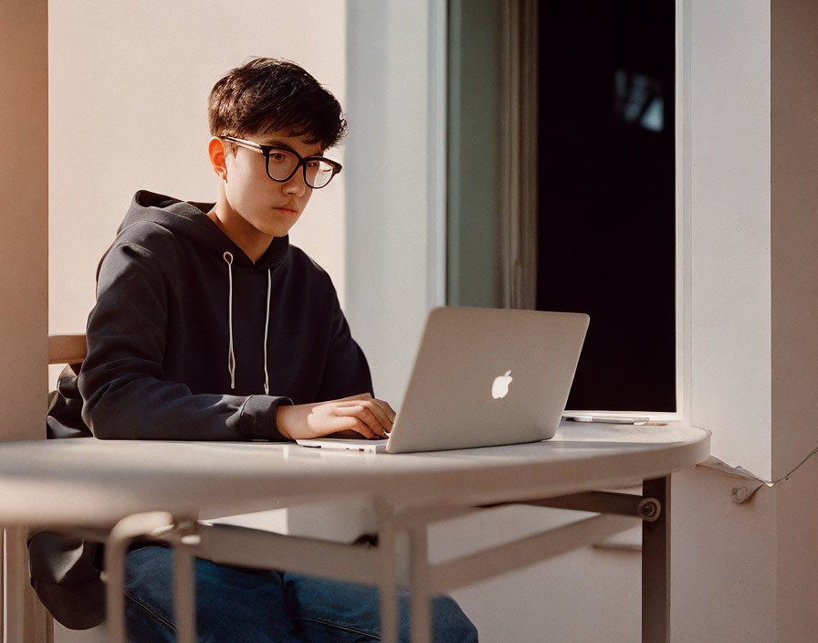 Person in Glasses Working on Laptop at White Table