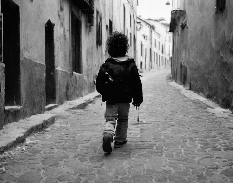 Black and white photo of child on cobblestone street