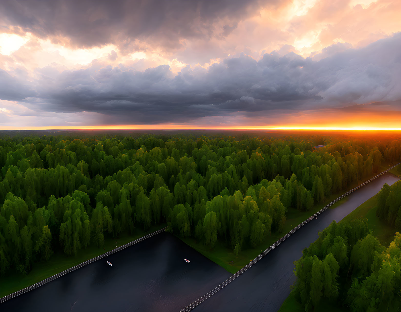 Vibrant orange sunset over dark storm clouds and green forest landscape