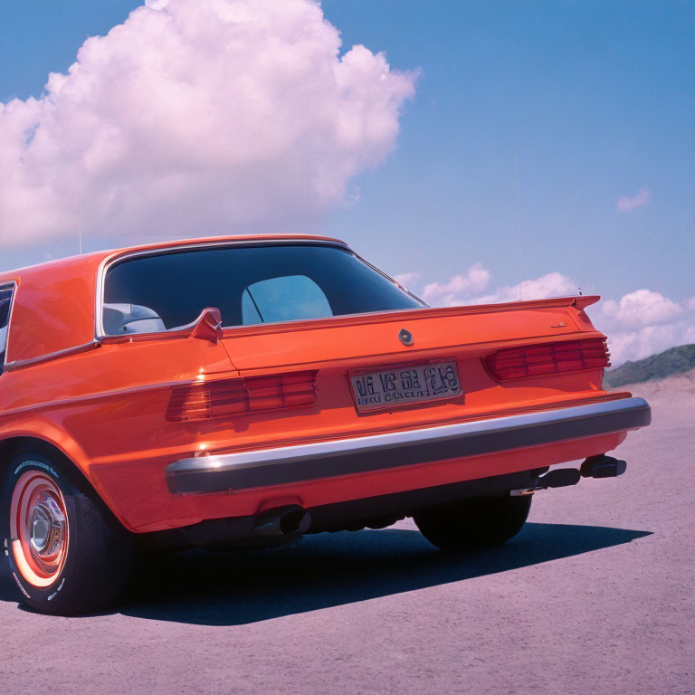 Vintage Orange Car with Distinctive Tail Lights and Chrome Bumper on Open Road