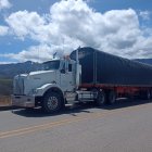 Blue semi-truck with flame decals on highway against mountain backdrop