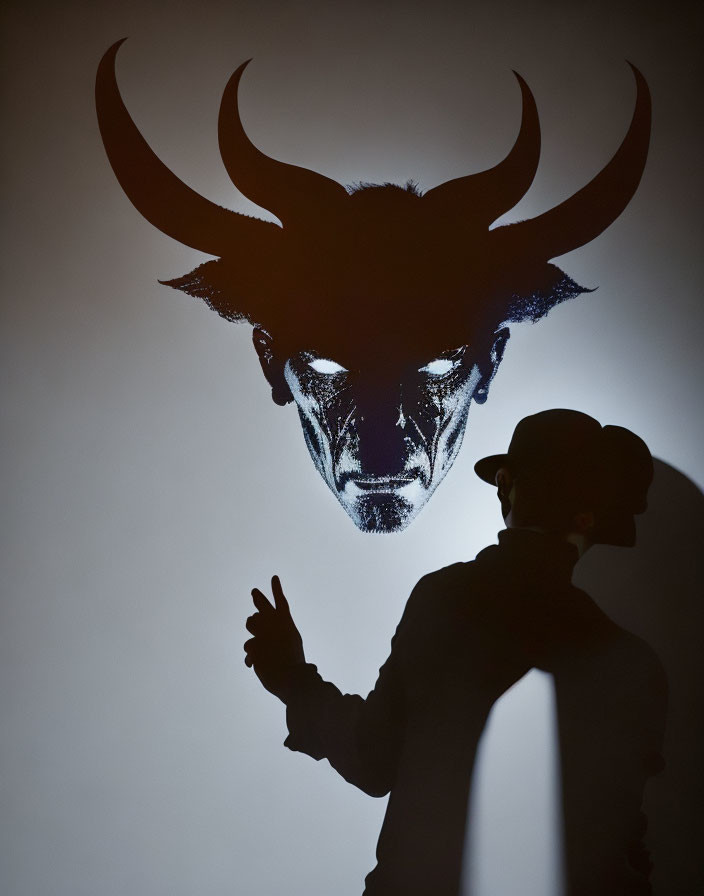 Shadow on wall aligns with devilish illustration, creating horn illusion