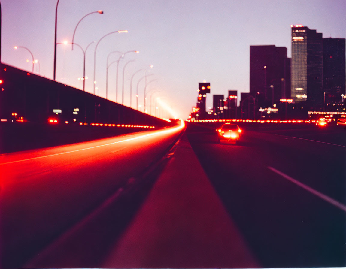 Cityscape at Twilight: Glowing Streetlights & Car Headlights on Curved Highway