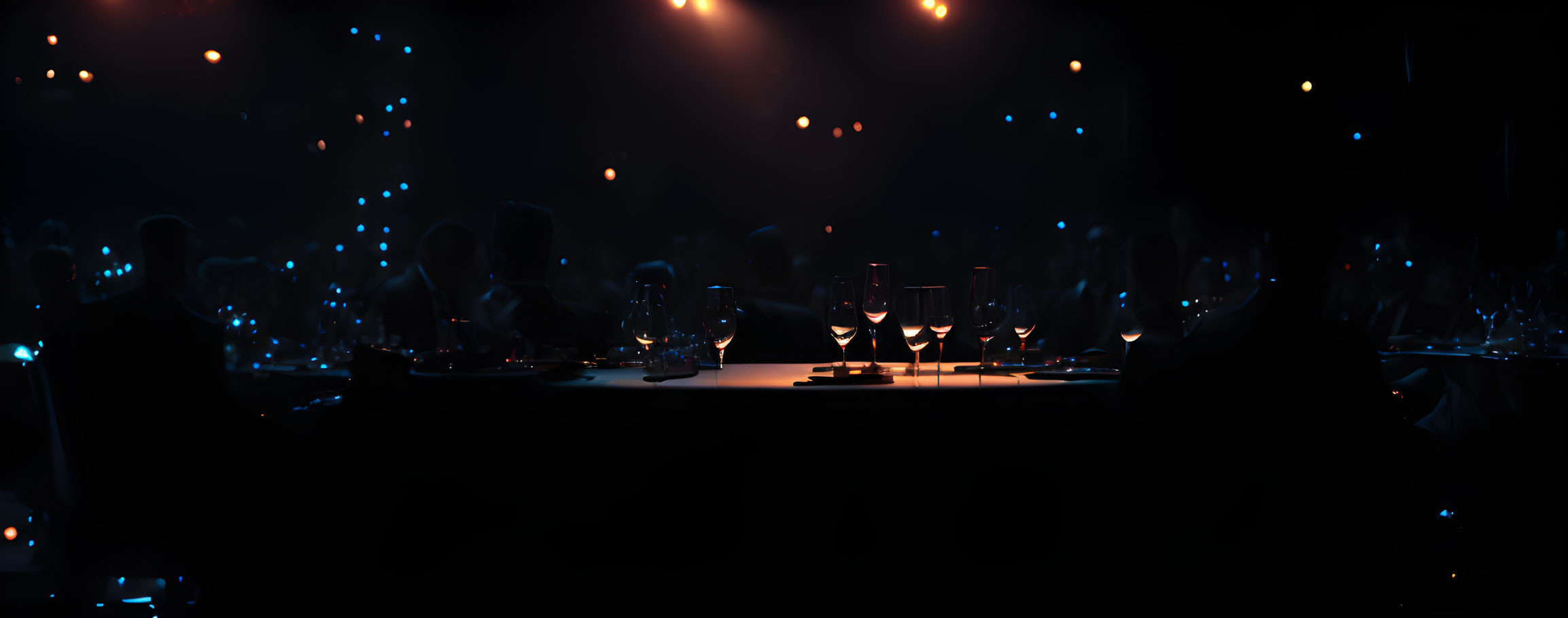 Dimly-lit banquet scene with silhouettes and wine glasses in atmospheric setting