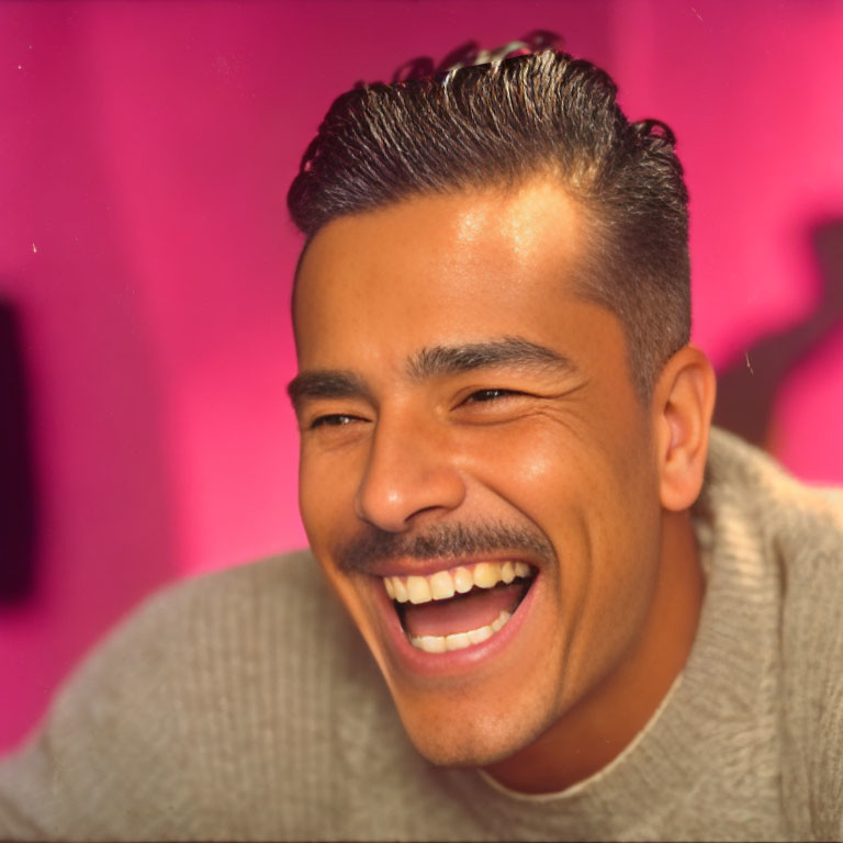 Smiling man with mustache in beige sweater on pink background