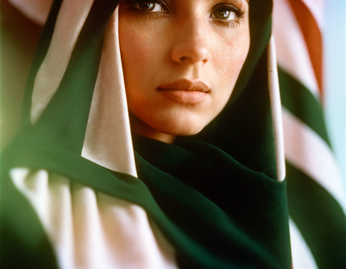 Close-up portrait of woman with striking eyes veiled by colorful fabric.