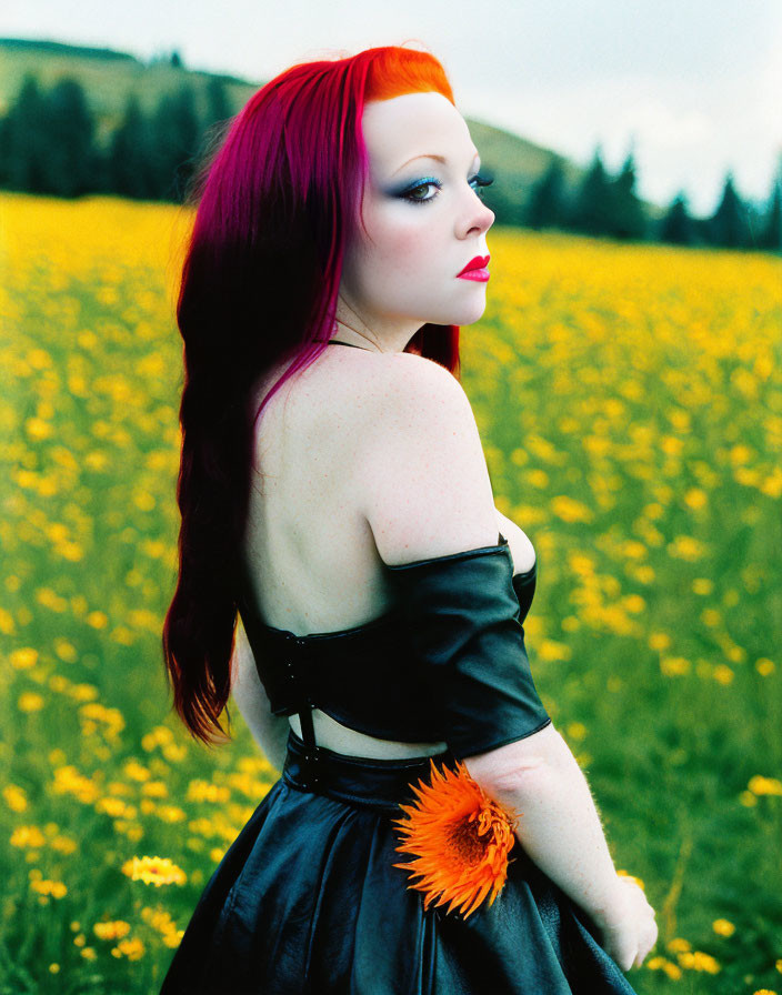 Woman with Red and Black Hair in Black Dress Holding Flower in Yellow Flower Field