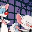 Two animated mice in front of grid window in industrial setting