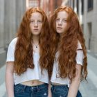 Identical women with long red hair in white and floral outfits on floral backdrop