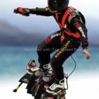 Futuristic motorcyclist in black and red suit on modern bike against cloudy sky