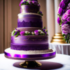 Three-tiered purple wedding cake with gold patterns and edible flowers on elegant tableware