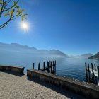 Tranquil lakeside scene with sailboats, hills, and sunny sky