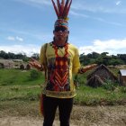 Indigenous person in feathered headdress in natural landscape