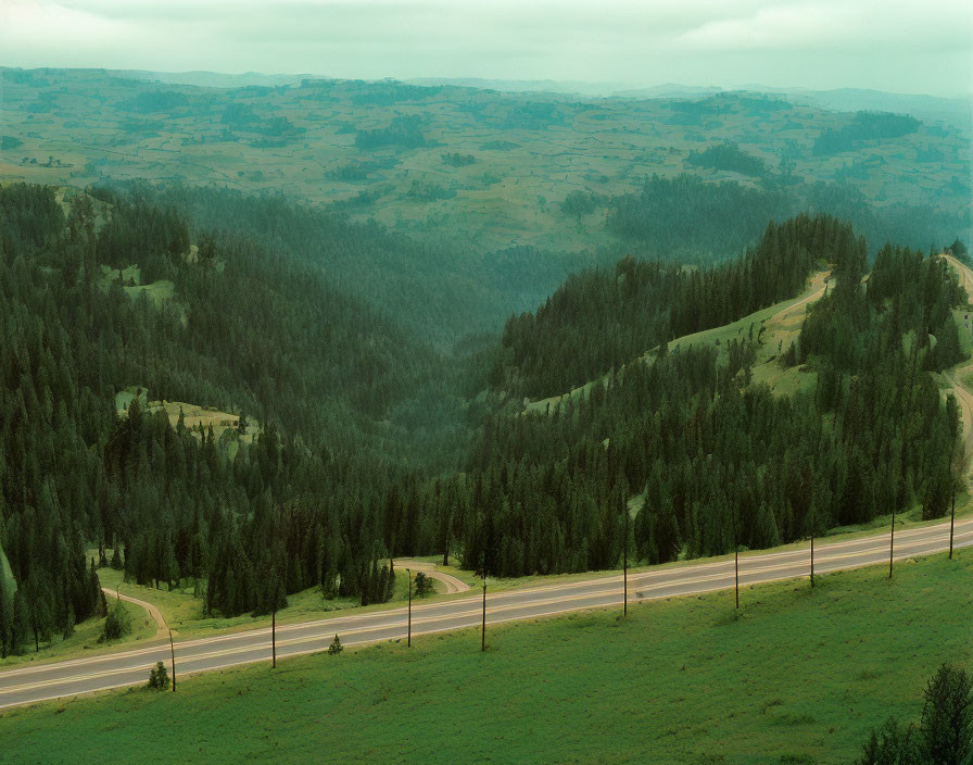 Scenic winding road through lush hilly landscape under overcast sky