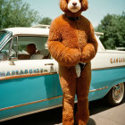 Person in Full-Body Bear Costume with Vintage Car on Clear Blue Skies