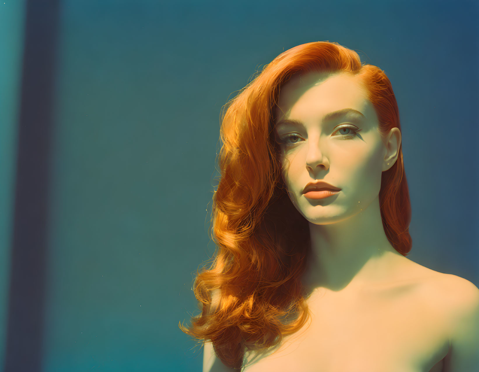 Red-haired woman with fair skin on blue background, serene expression.