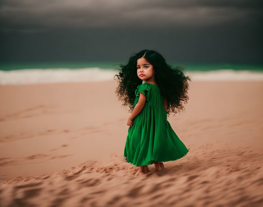 Young girl in green dress on sandy beach with cloudy skies