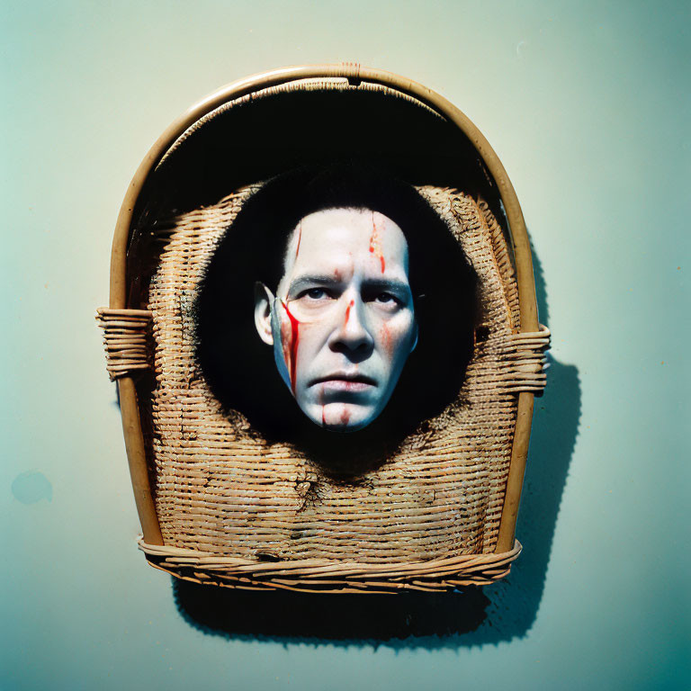 Man's face with tribal white patterns in woven basket on green background