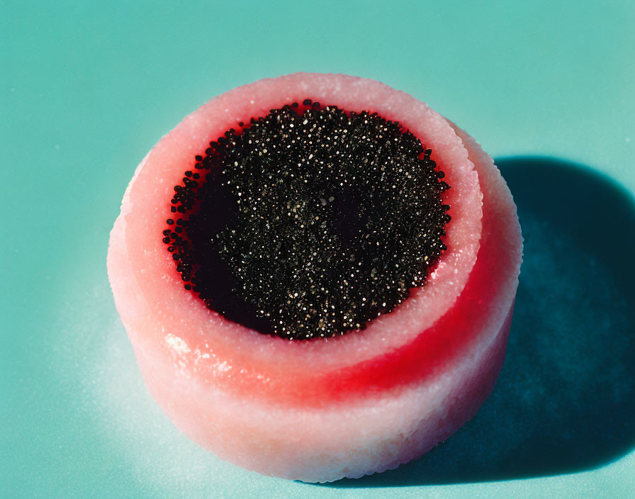 Close-Up of Pink Jelly Candy with Black Sugar Beads on Blue Background