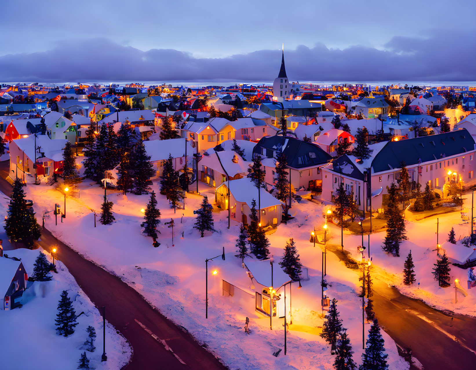 Snow-covered town with colorful houses and church spire at twilight