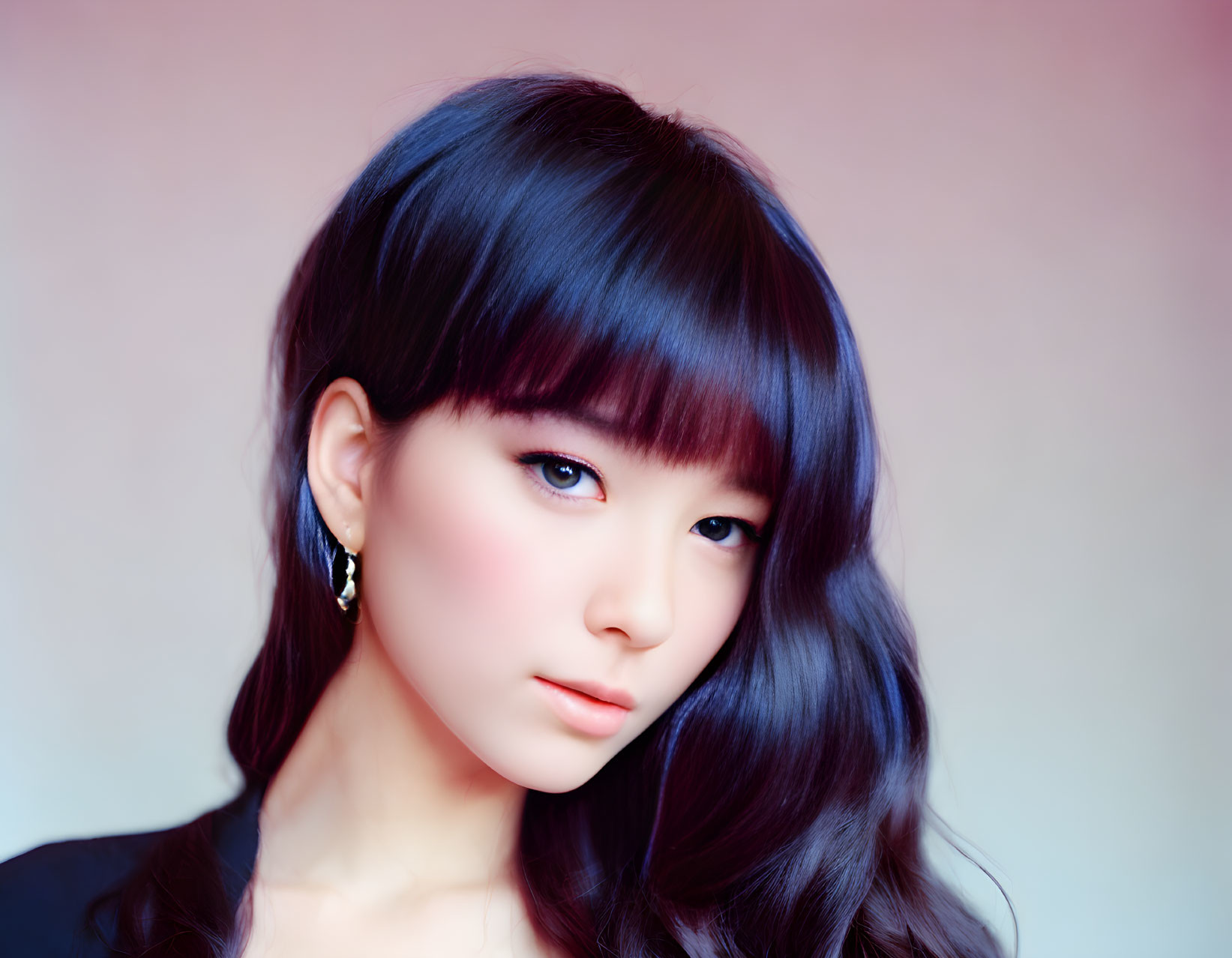 Portrait of woman with dark hair, bangs, fair skin, subtle makeup on pink and blue backdrop